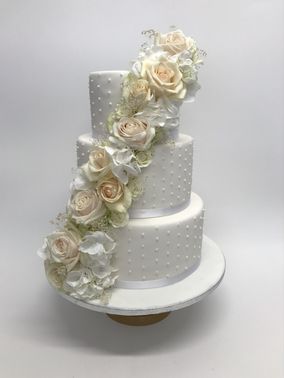 weiße Hochzeitstorte mit Zuckerperlen und weißen Rosen – gesehen bei frauimmer-herrewig.de