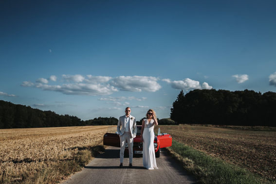 Brautpaar vor rotem Auto – gesehen bei frauimmer-herrewig.de