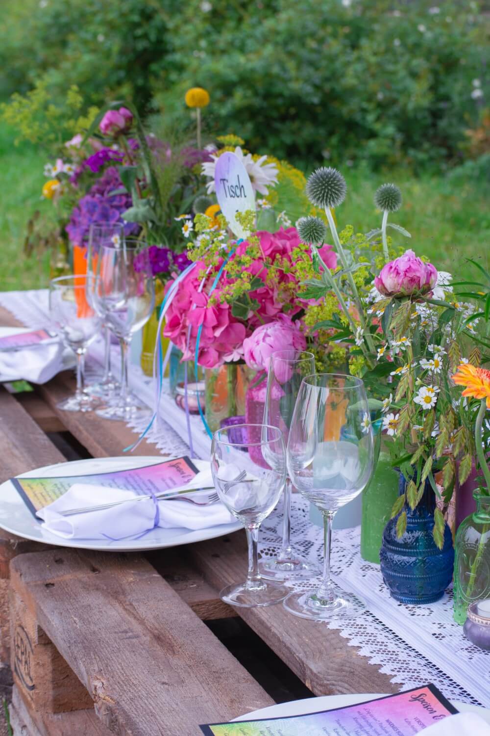 Bunte Tischdeko mit Blumen für Outdoor-Hochzeit – gesehen bei frauimmer-herrewig.de